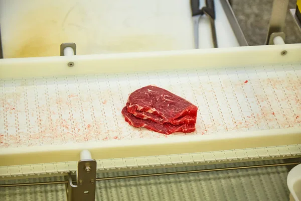 Meat processing plant. Slices of cut beef on the conveyor.