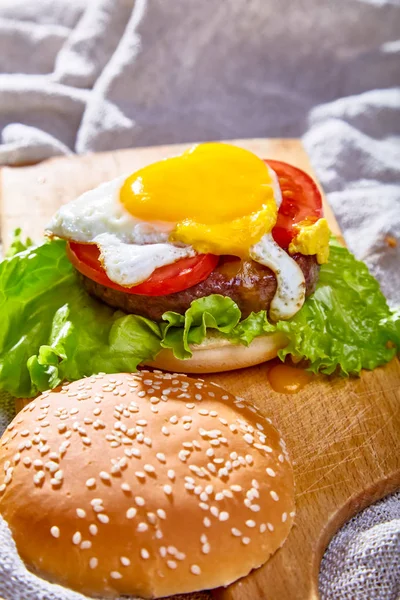 Burger con costoletta, pomodori e uova è su una tavola di legno — Foto Stock