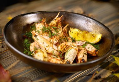 Limonlu ve dereotlu kızarmış karides tabakta.