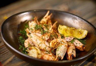 Limonlu ve dereotlu kızarmış karides tabakta.