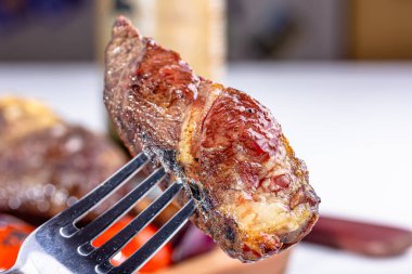 Bir tabak etin arka planındaki çatala saplanmış bir biftek..