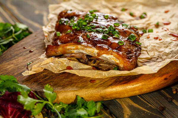 Pork ribs with green onions baked with sauce lie on a wooden Board