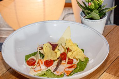 Jambonlu salata, domates, marul ve patates kızartması tabakta.