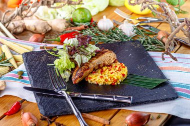 Tabakta pirinçli biftek ve sebze var.