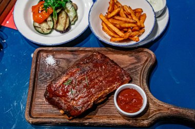 Ahşap bir tahtanın üzerinde sebzeli domuz pirzolası var.