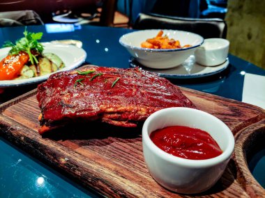 Ahşap bir tahtanın üzerinde sebzeli domuz pirzolası var.