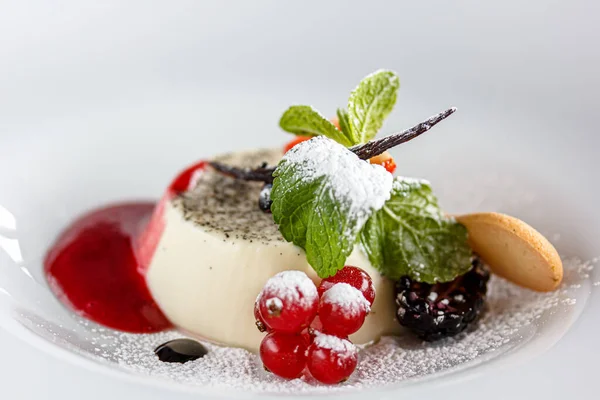 Böğürtlen soslu panakota ve taze çilek, böğürtlen ve kırmızı frenk üzümü tabakta.