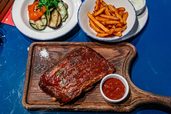 Ahşap bir tahtanın üzerinde sebzeli domuz pirzolası var.