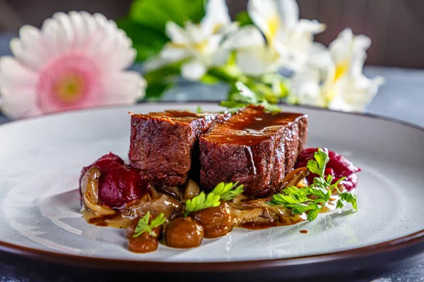 Grilled beef with mushrooms, mashed potatoes and beetroot sauce is on the plate