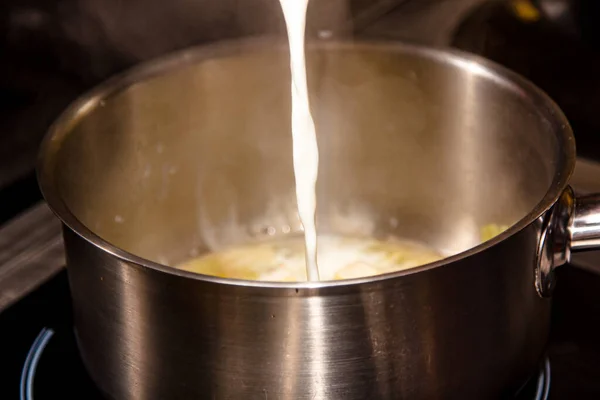 Cooking dishes from milk. Milk is poured in a trickle into a saucepan.