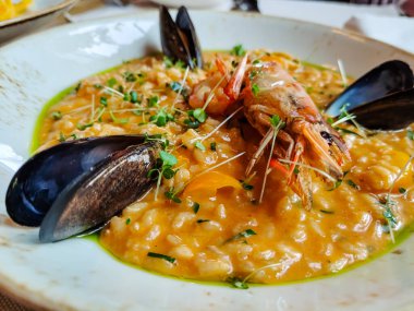 Tabakta deniz ürünleri, langoustines ve midye ile risotto var..