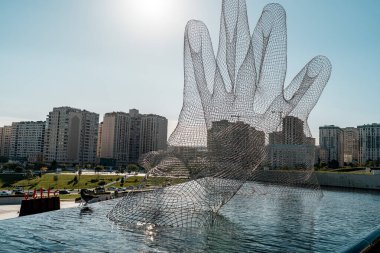 Bakü, Azerbaycan - 18 Mayıs 2025: Lorenzo Quinn tarafından birlikte, Heydar Aliyev Merkezi 'nde suyun üzerindeki iki elin kablo çerçeveli heykeli, birlik ve bağlantıyı simgeliyor.