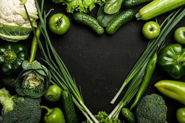 Овощи в форме сердца. Фотография сердца из разных овощей на черном фоне. Копирование пространства, вид сверху
