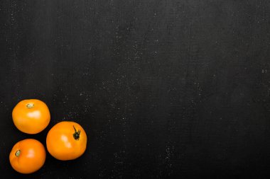 Rustik siyah zemin üzerine sarı domates. Taze sebze, üstten görünüm
