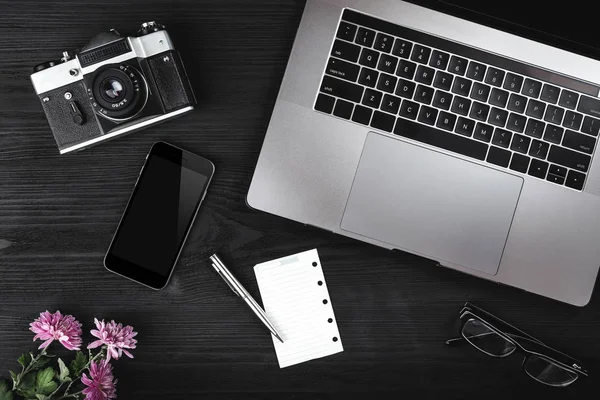 Notebook klavye, kamera, akıllı telefon, ahşap zemin üzerine gözlük ile çalışma alanı. Yukarıdan görünüm, ofis masa masası