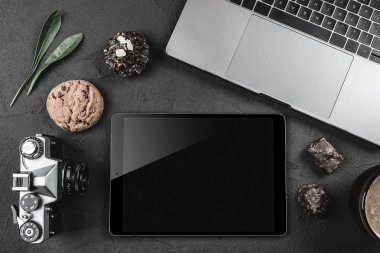 Bir taş yüzeye iş, bir kamera, bir grafik tablet veya ipad ve tatlılar için bir dizüstü bilgisayar var. Üstten görünüm, düz yatıyordu stili