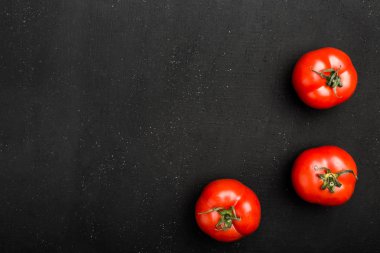 Kopya alanı siyah bir zemin üzerine taze domates. Mevsim sebzeleri, üstten görünüm