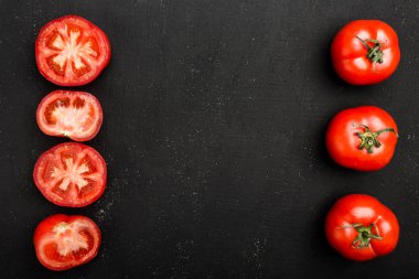 Bütün domates ve yarım kırmızı domates siyah taş zemin üzerine yalan. Taze ve succulents sonbahar sebze, kopya alanı