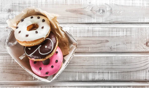 Sweet donuts on an old wooden table, placed in a box. Top view and space for text