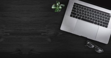 Dizüstü bilgisayar ve gözlük siyah ahşap masa. İş kavramı, üstten görünüm ve kopya alanı