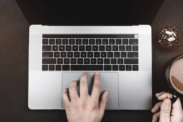 顶部视图 男性的手使用在银色笔记本电脑与空白黑屏幕和喝咖啡 — 图库照片