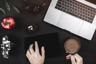 App dijital tablet ile kullanan adam. Laptop ve kulaklık en iyi görünümünü düz siyah bir tablo üzerinde yatıyordu