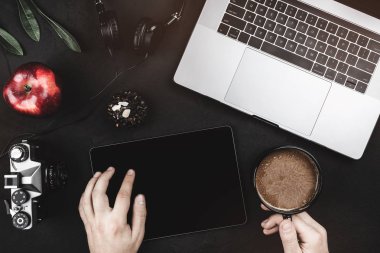 Erkek elini üstten görünüm boş ekranda siyah tablet. Vintage taş zemin, üstten görünüm üzerinde dizüstü bilgisayarla çalışma alanı