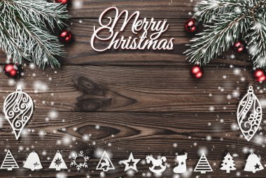 Bir Merry Christmas yazıt ve el yapımı ağaç oyuncak ve ahşap zemin, kar etkisi üzerine kırmızı küre ile yaprak dökmeyen şube yukarıdan görüntülemek