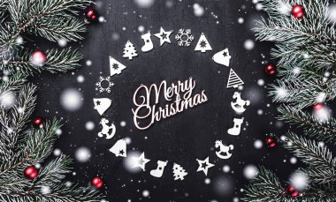 Üst, üst, görüntülemek yukarıdan, el yapımı ahşap oyuncaklar çemberi yuvarlak şekli, herdem yeşil dallarda siyah arka plan ve beyaz Merry Christmas yazıt, tebrik.