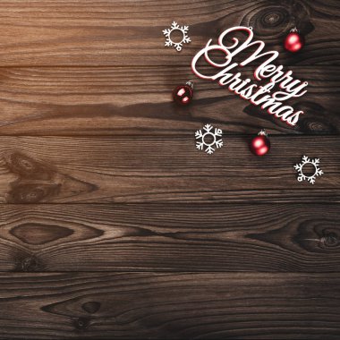 Bir Merry Christmas yazıt ve el yapımı ağaç oyuncak ve ahşap zemin, tebrik kartı, ampuller ile yazma metin için yer ile üzerine kırmızı Küre yukarıdan görüntülemek