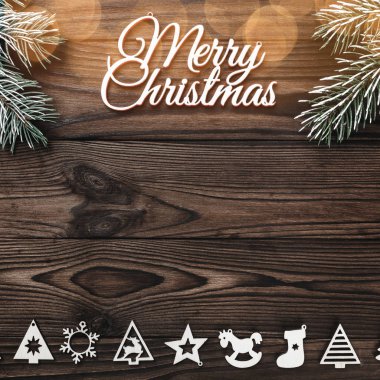 Bir Merry Christmas yazıt ve el yapımı ağaç oyuncak ve ahşap arka plan, tebrik kartı, ampuller ile yazma metin için yer ile üzerinde evergreen şube yukarıdan görüntülemek