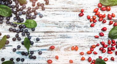 Mavi çilek ve ahşap rustik zemin üzerine fesleğen yaprakları ile brier meyvesi. Üstten görünüm, yazma, düz alan yatıyordu