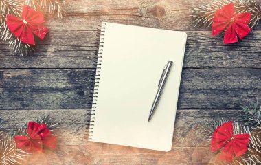 Kırmızı ok ve xmas el yapımı oyuncak ahşap gri arka plan üzerinde dört çam dalları ve kalemle metin yazma, Noel tebrik kartı için bir not defteri