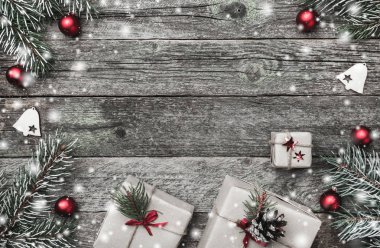 Eski ahşap arka plan üzerinde Noel kartı. Hediyeler, kırmızı topları ve el yapımı oyuncak. Metin için yer. Üstten görünüm. Işıklar ve kar etkisi
