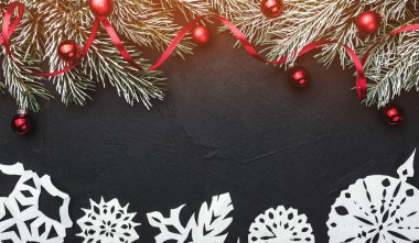 Noel kartı. Siyah taş zemin üzerine. Topları ve kırmızı bolluk süslü çam dalları ile. Üstten görünüm. Kağıt pul el yapımı. Metin için yer