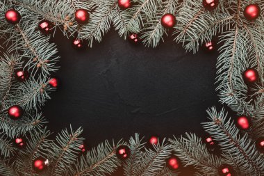 Noel tebrik kartı siyah arka plan. Çerçeve köknar dalı kırmızı topları ile dekore edilmiştir. Senin için metin alanı