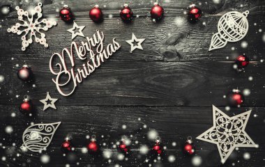 Metin için yer ile neşeli Noel tebrik kartı. Noel baubles, süslü Ahşap oyuncaklar ve koyu ahşap arka plan üzerinde kar etkisi