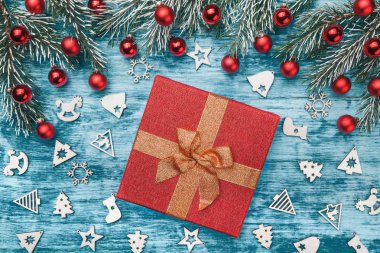 Noel ve mutlu yeni yıl kompozisyon. Güzel hediye altın şerit üzerinde çam dalları, kırmızı baubles ve Ahşap oyuncaklar ile mavi arka plan ile. Üstten görünüm