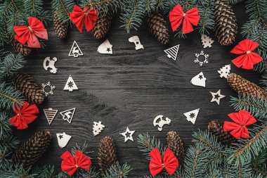 Noel tebrik kartı. Metin için yer. Çam dalları koniler ve siyah ahşap zemin üzerine kırmızı kaseler ile. Noel oyuncaklar. Üstten görünüm