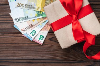 Ahşap arka plan, farklı değer para ve değerli bir hediye. Üstten görünüm.