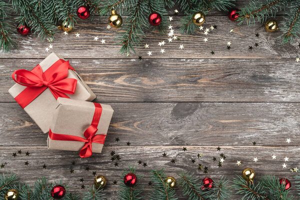 Old wooden Christmas background. Fir branches with baubles and gold stars. Xmas gifts. Top view.