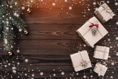 Koyu ahşap arka plan üzerinde hediye kutuları. Üstten görünüm. Köknar ağacı baubles, metin için yer. Işık ve kar taneleri etkisi.