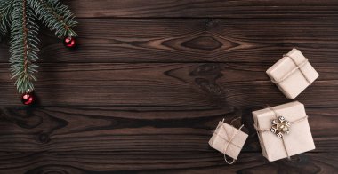 Koyu ahşap arka plan üzerinde hediye kutuları. Üstten görünüm. Çam ağacıyla baubles, metin için yer. 