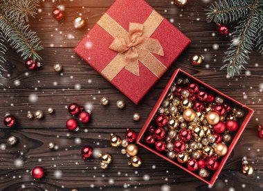 Hediye kutuları kahverengi ahşap zemin üzerinde toplar. Köknar ağacı baubles, metin için yer. Üstten görünüm. Işık ve kar taneleri etkisi.