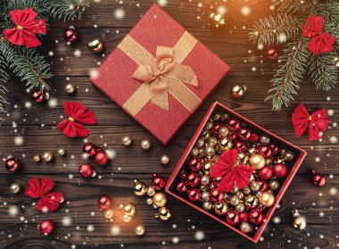 Hediye kutuları kahverengi ahşap zemin üzerinde toplar. Köknar ağacı baubles, metin için yer. Üstten görünüm. Işık ve kar taneleri etkisi.