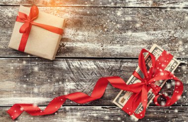 Eski ahşap, para kırmızı bolluk ve hediye ile süslenmiş Noel arka plan. Üstten görünüm. Işık ve kar taneleri etkisi.