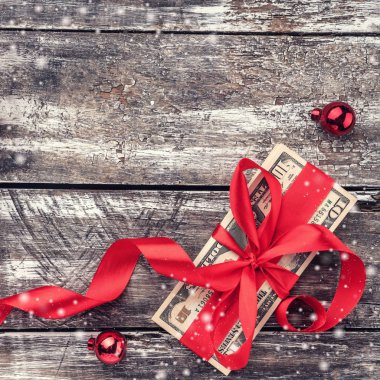 Bir Noel hediyesi, para, Xmas öğeleri, ahşap arka plan üzerinde. Üstten görünüm. Etkisi kar taneleri.