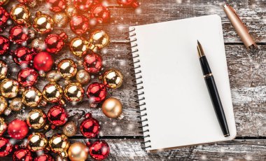 Noel kartı. Eski ahşap arka plan, baubles yarısı dolu. Ve bir tebrik mesajı için bir not defteri. Üstten görünüm. Noel kartı. Işık ve kar taneleri etkisi.