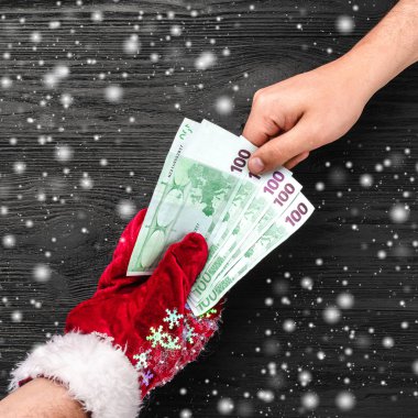 Siyah ahşap arka plan. Noel Baba'nın hediye. Noel kartı. Üstten görünüm. Xmas tebrikler. Baba para veriyor. Etkisi kar taneleri.