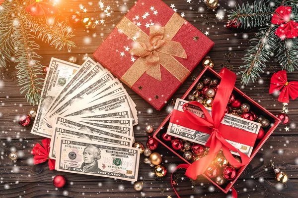 A Christmas gift, money, Christmas items, on a wooden background. Top view. Effect of light and snowflakes.